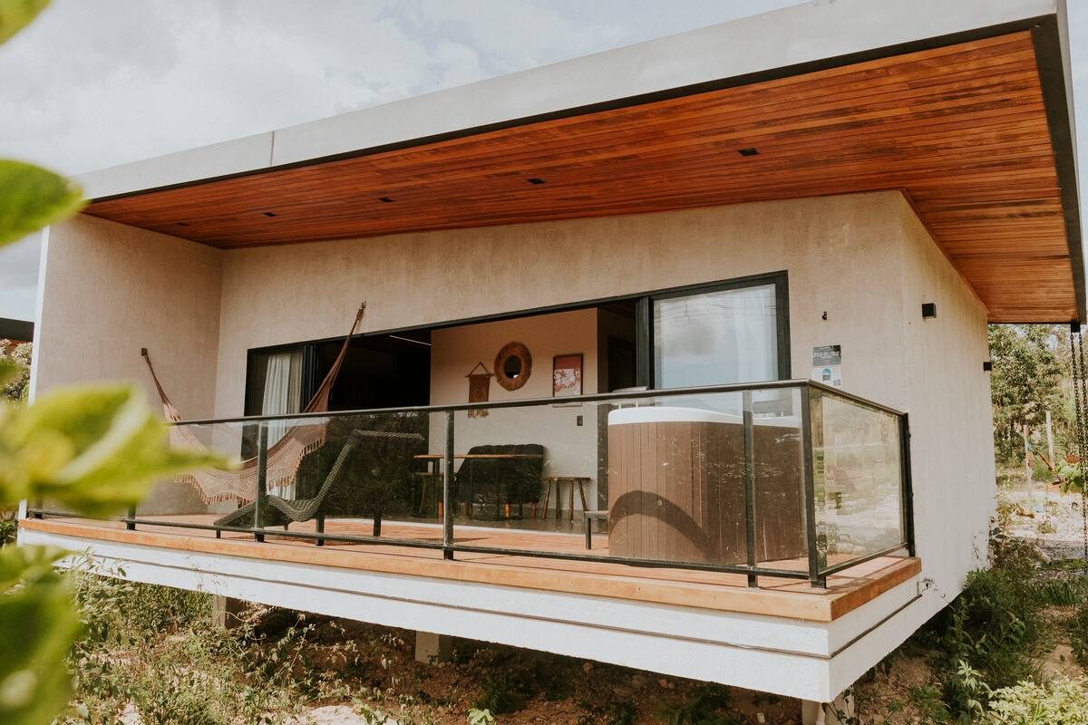 Varanda da Casa Turmalina com rede armada, ofurô e teto de madeira inclinado
