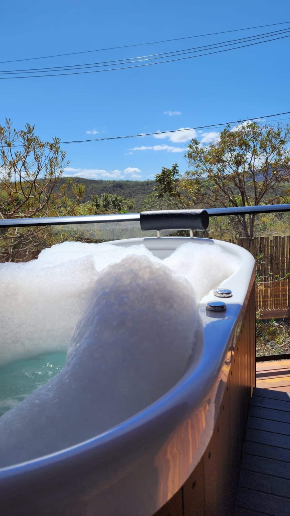 Ofurô da Casa Turmalina coberto de espuma, com as montanhas do cerrado no horizonte