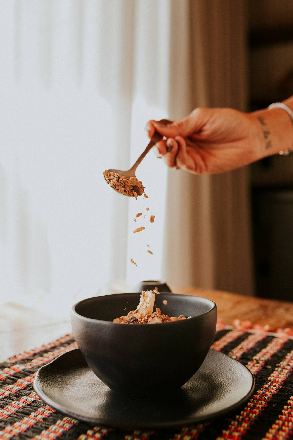 Granola sendo servida em tigela de cerâmica preta na mesa de café da manhã da Casa Turmalina