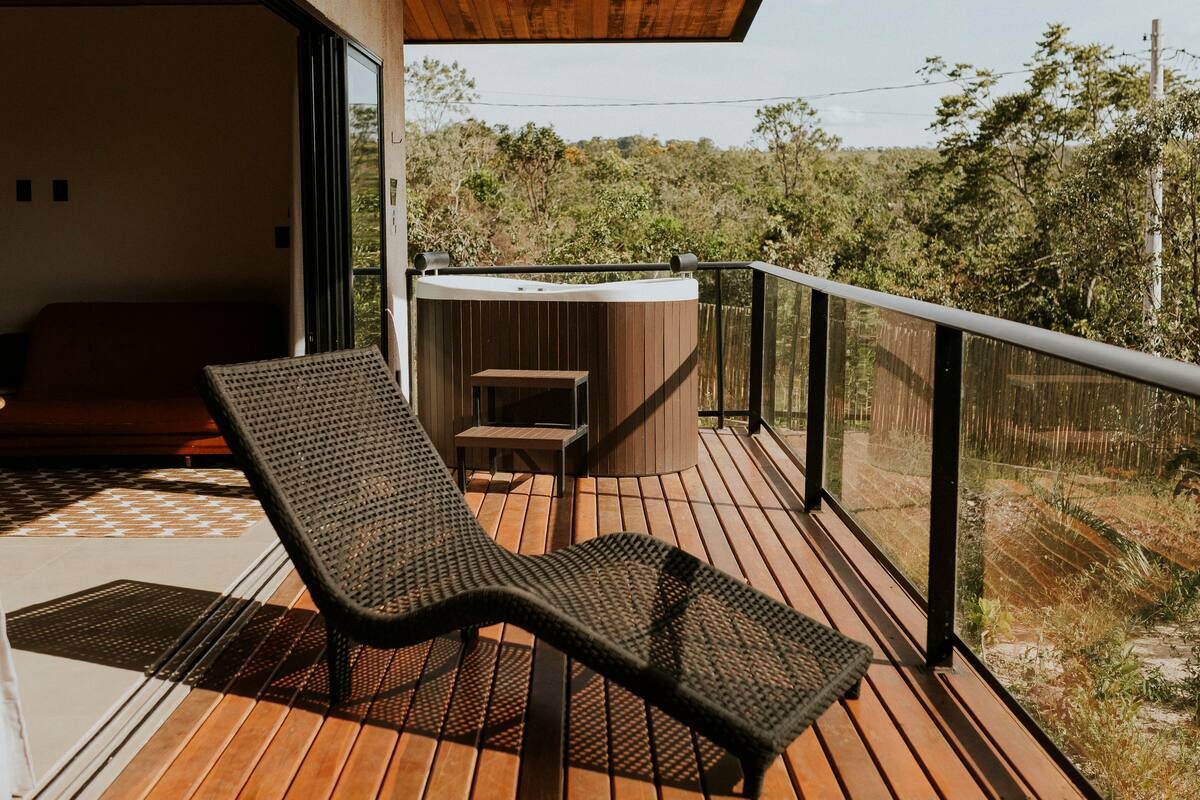 Deck de madeira da Casa Turmalina com espreguiçadeira de fibra, ofurô e vista aberta para o cerrado